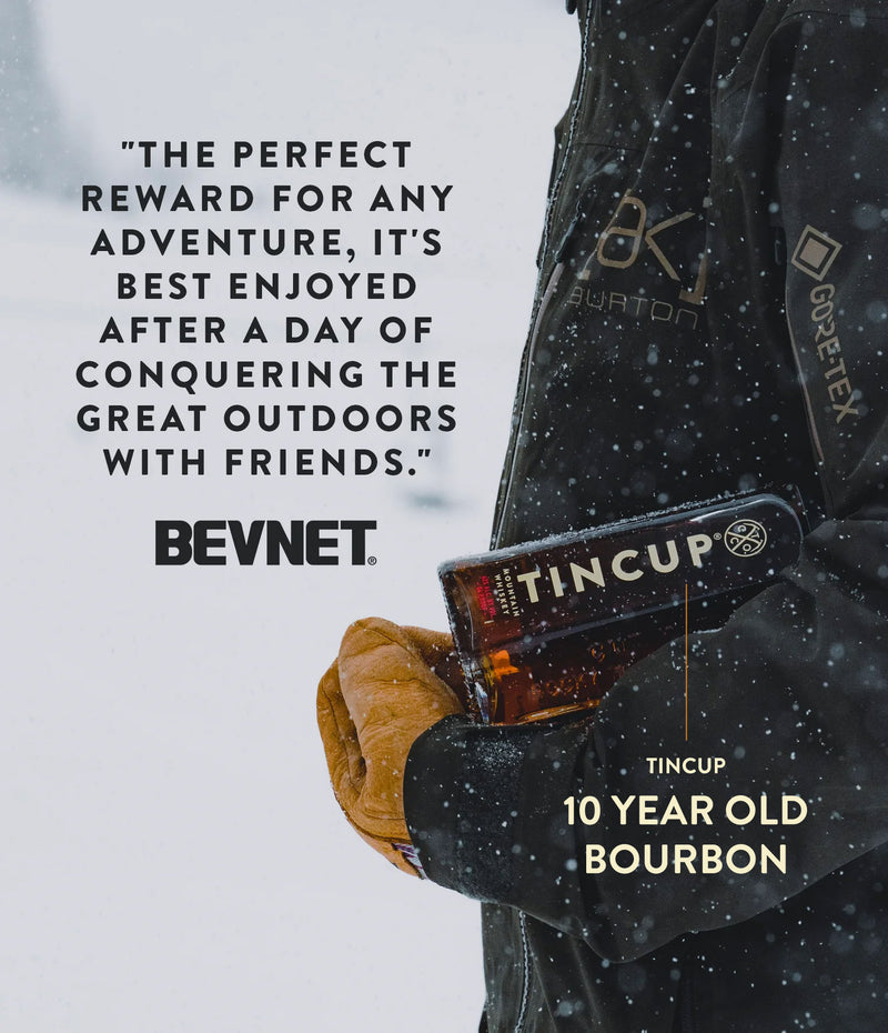 TINCUP 10 Year Bourbon Whiskey held by a hiker in a snowy landscape